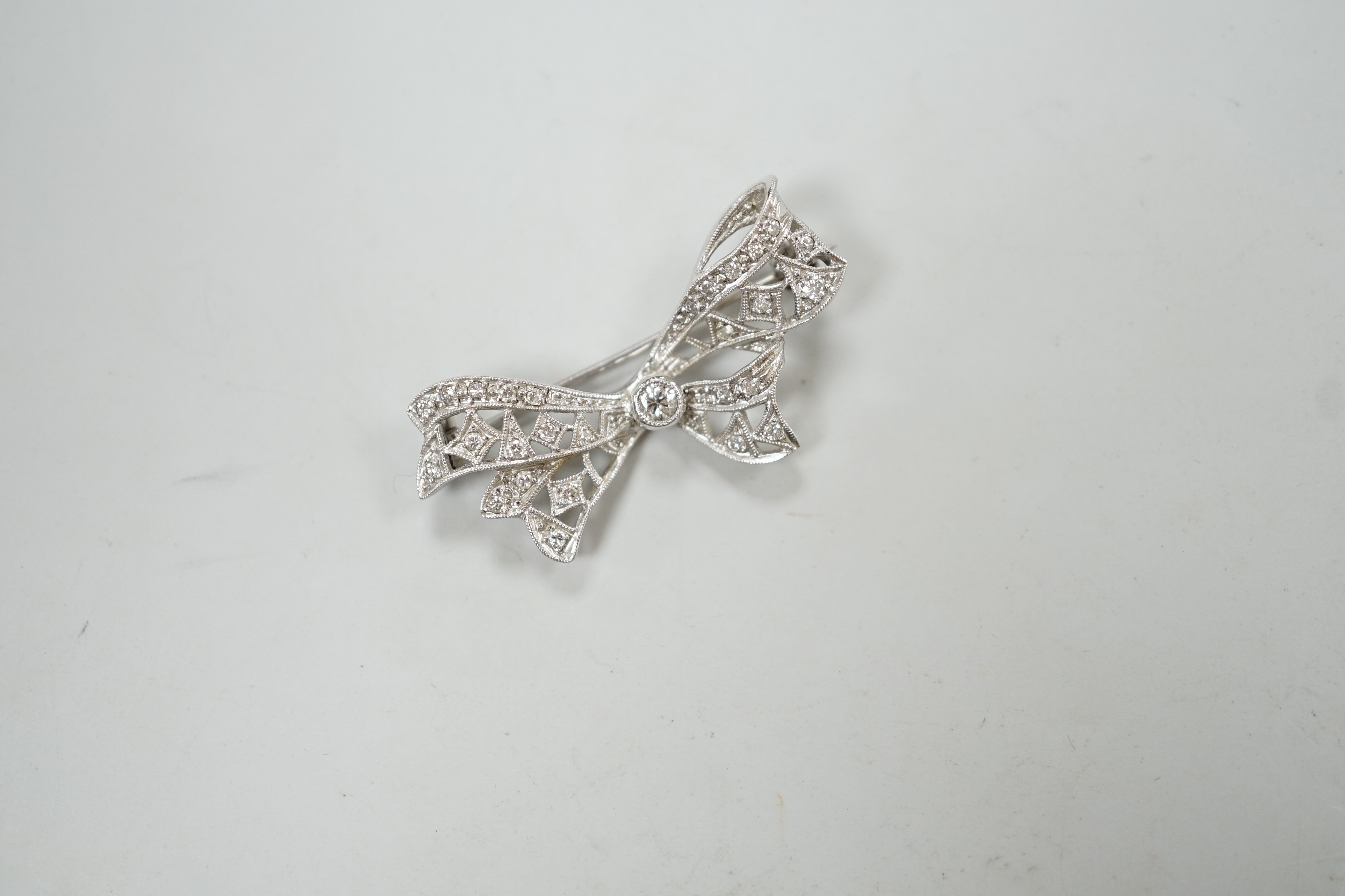 A white metal and diamond cluster set ribbon bow brooch, 36mm, gross weight 4 grams.